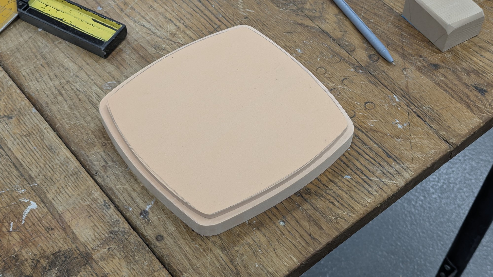 The same foam model on a workshop bench beside marking tools