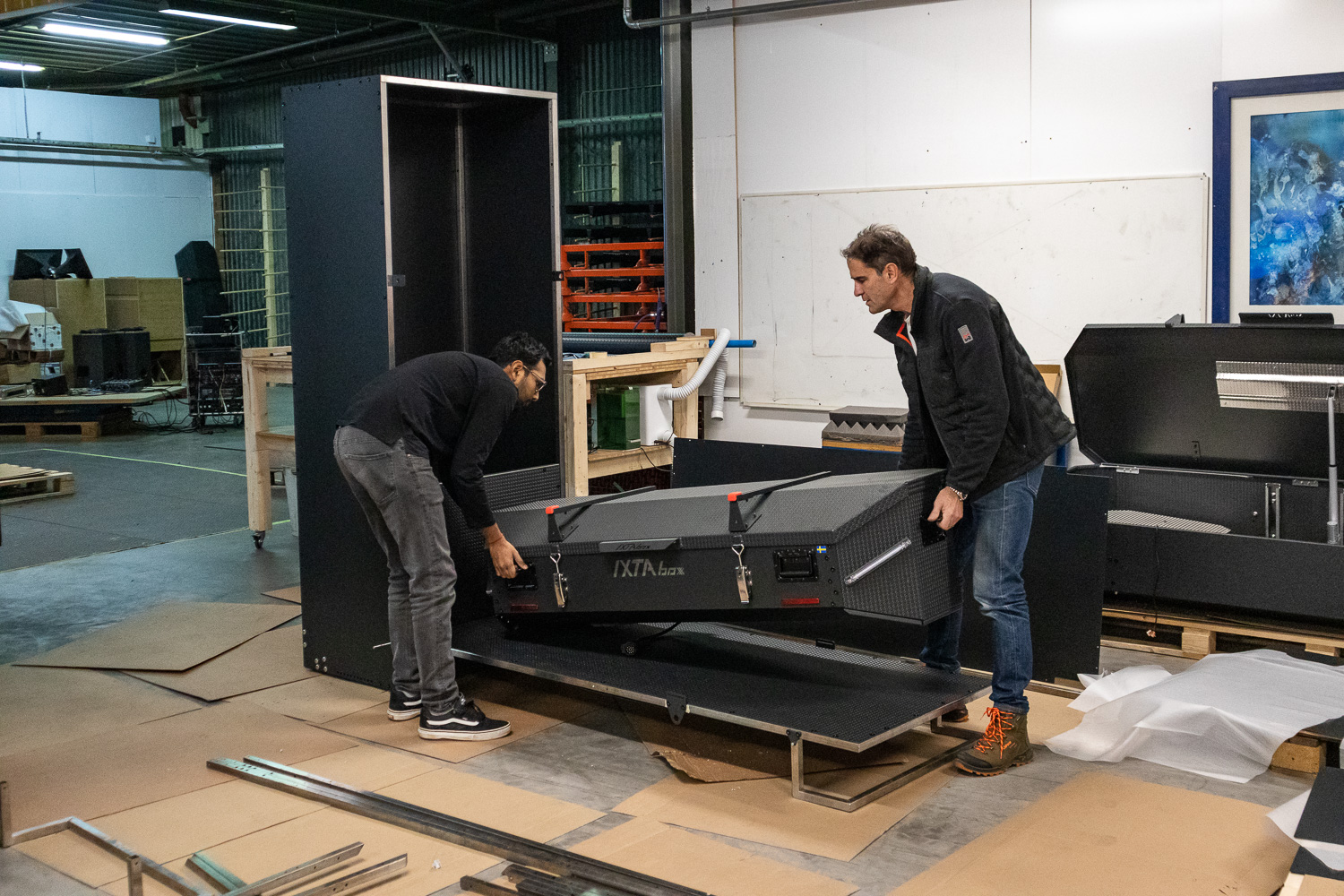Two people moving the finished box in the workshop