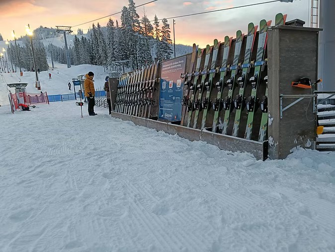 Self-service ski rental station at the base of a ski slope at dusk